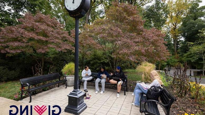 Students sitting on benches around a vintage clock